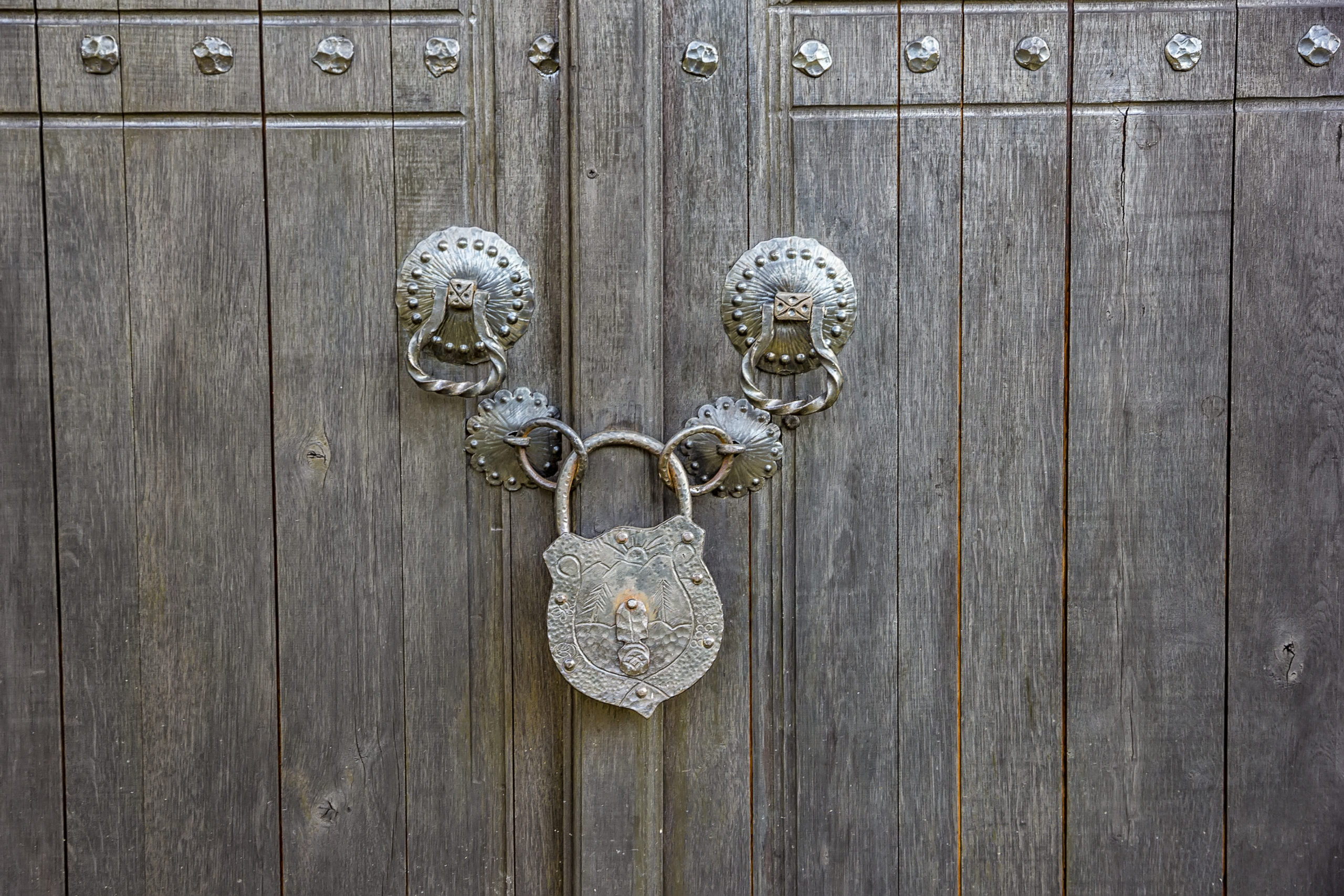 An old wooden door locked with a big vintage padlock. True vintage style